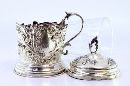 Porta copos em prata recortada com cartela para monograma envolvido por motivos florais e volutas, tampa com pomo e vidro com gravados a ácido.